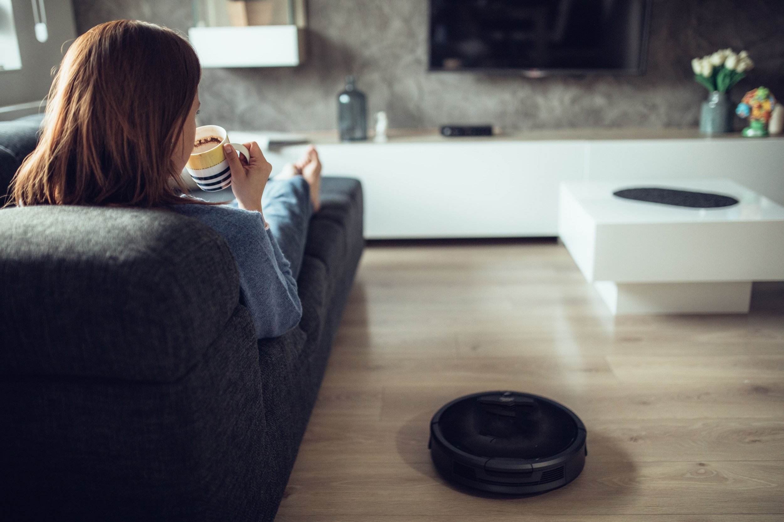 Sredstva za čišćenje doma u ponudi centra Supernova Zadar Woman relaxing on sofa next to vacuum cleaner robot